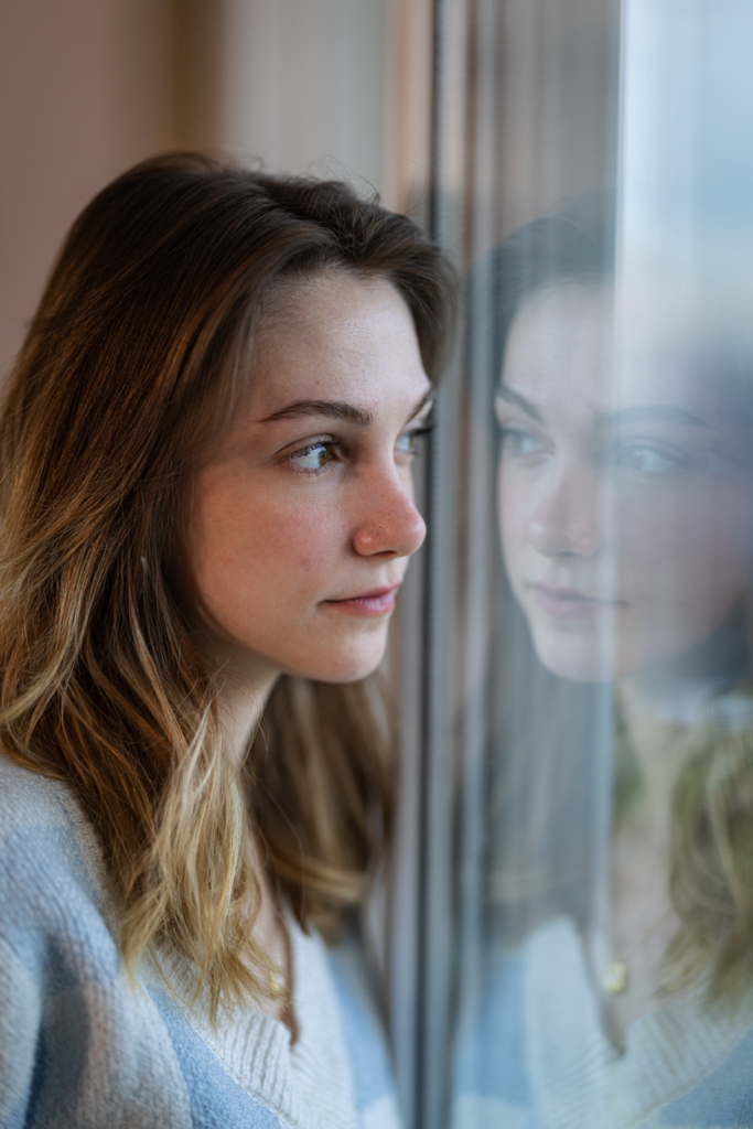 Fiatal lány az ablak előtt áll