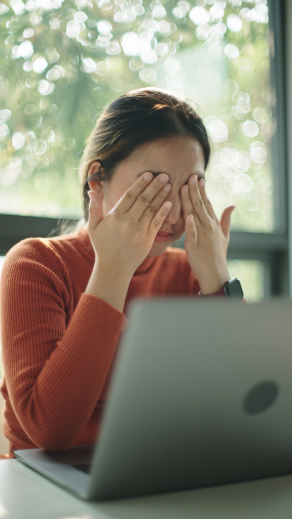 Nő a szemeit dörzsöli a laptopja előtt ülve