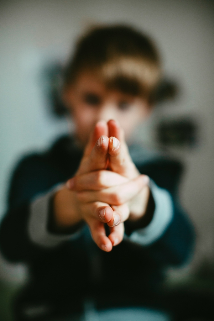 Kisfiú a kezével egy fegyvert formáz és a kamera felé tartja