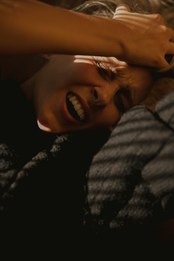 Nő arca eltorzul a fejfájástól, közben a kezével fogja a fejét