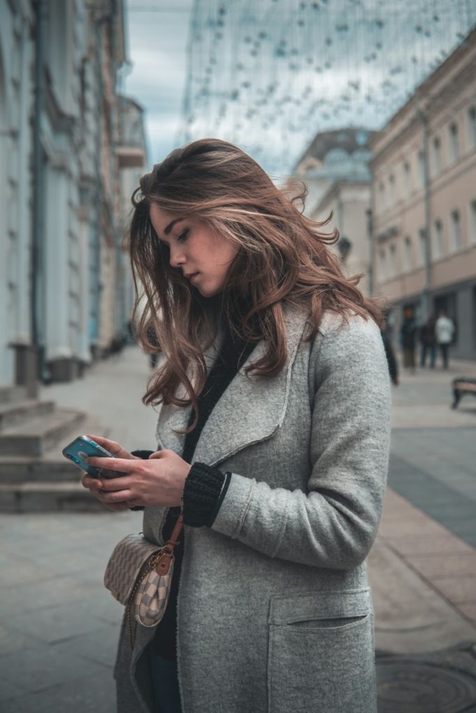 Lány a mobilját olvassa az utcán