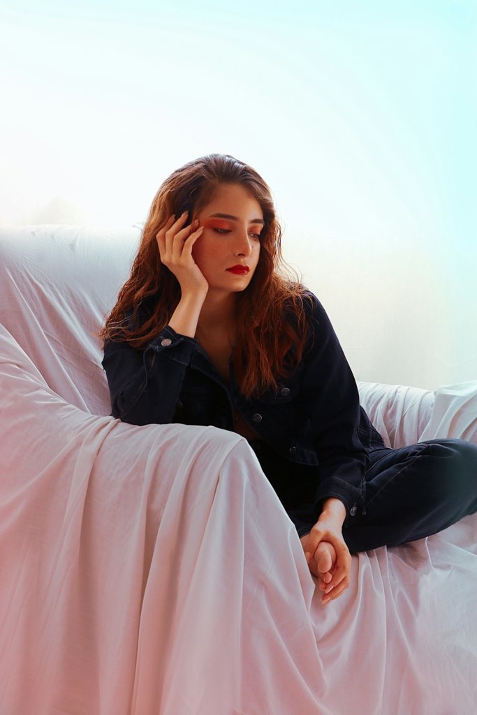 Fiatal nő elgondolkodva ül egy fehér lepedővel takart fotelban