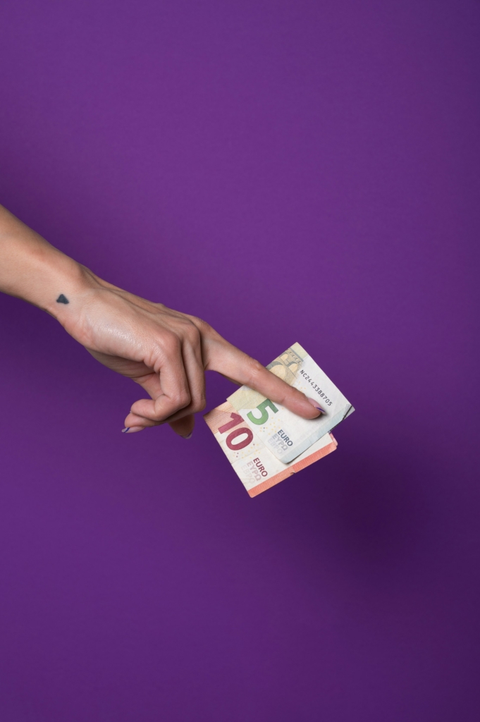 Nő a két ujja közt pár eurót tart