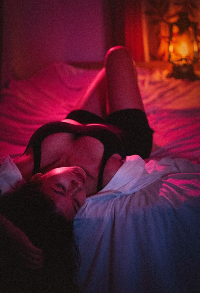 Nő fehérneműben az ágyban lila és rózsaszín neon fényben