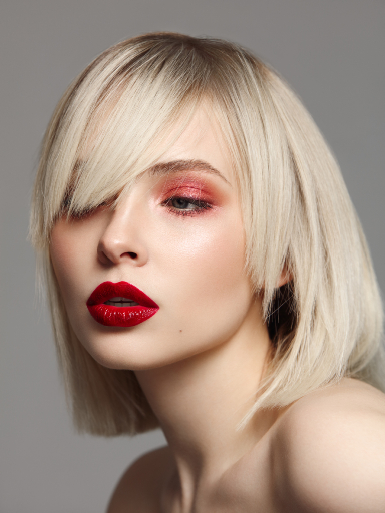 Szőke nő határozott oldalfrufruval glam sminkben