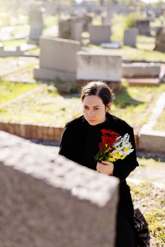 Fiatal nő virágot visz a temetőre