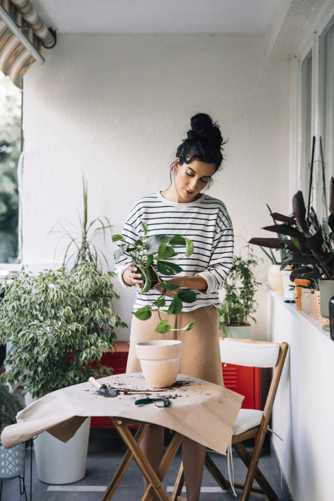 Nő zöld növényeket ültet az erkélyén