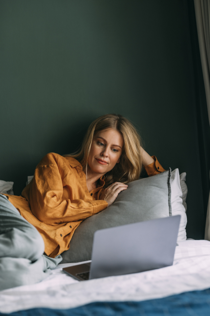 Nő az ágyban fekve laptopozik
