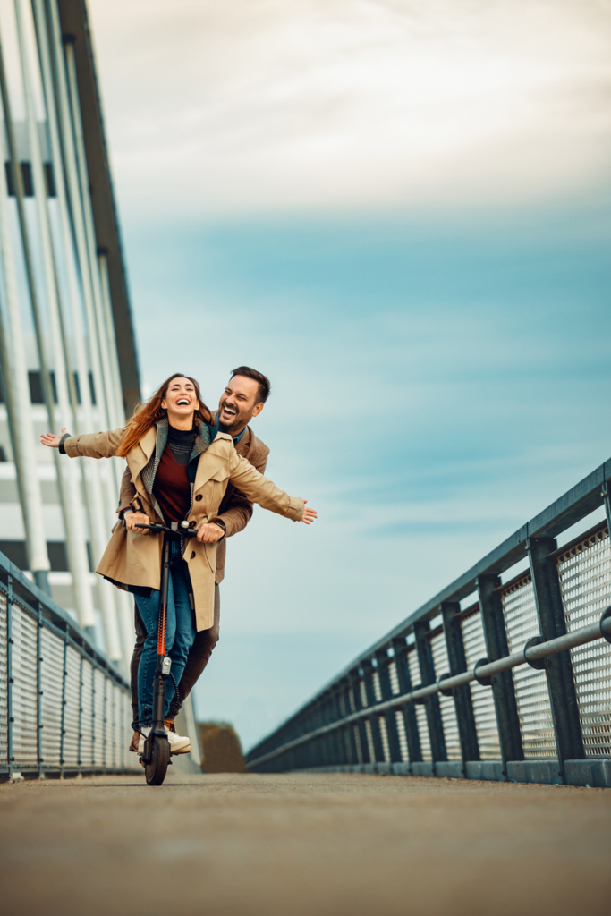 Boldog pár rollerezik egy hídon