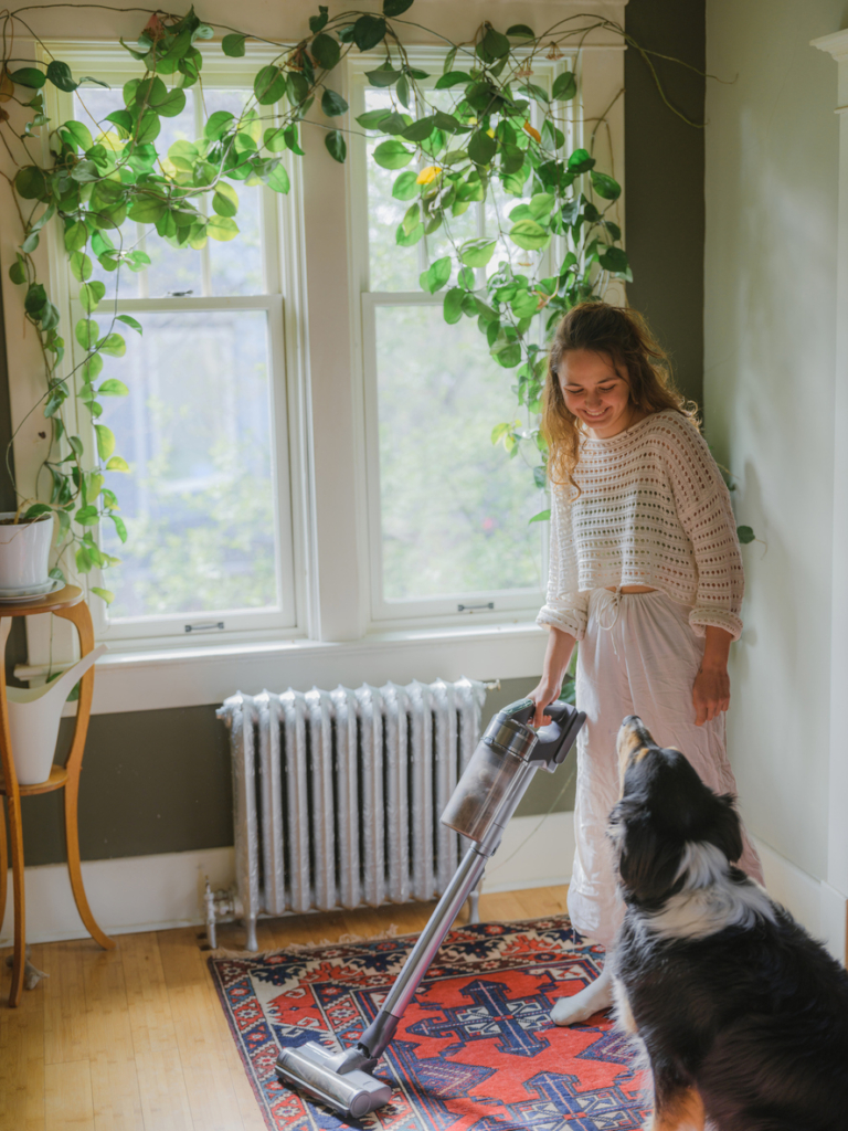 Nő otthon porszívózik a kutyájával