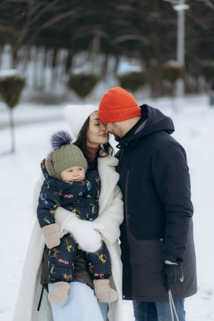 Famiglia felice insieme nella neve - papà, mamma e il loro bambino in braccio