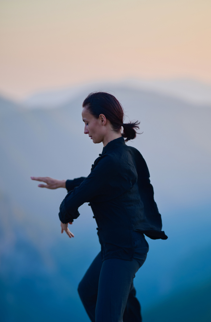 Nő a tai chi-t gyakorolja napfelkeltekor a hegyen