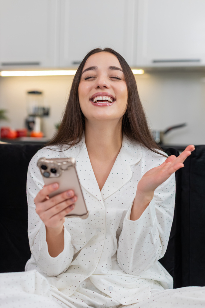 Nő nagyon örül, miközben a telefonját nézi