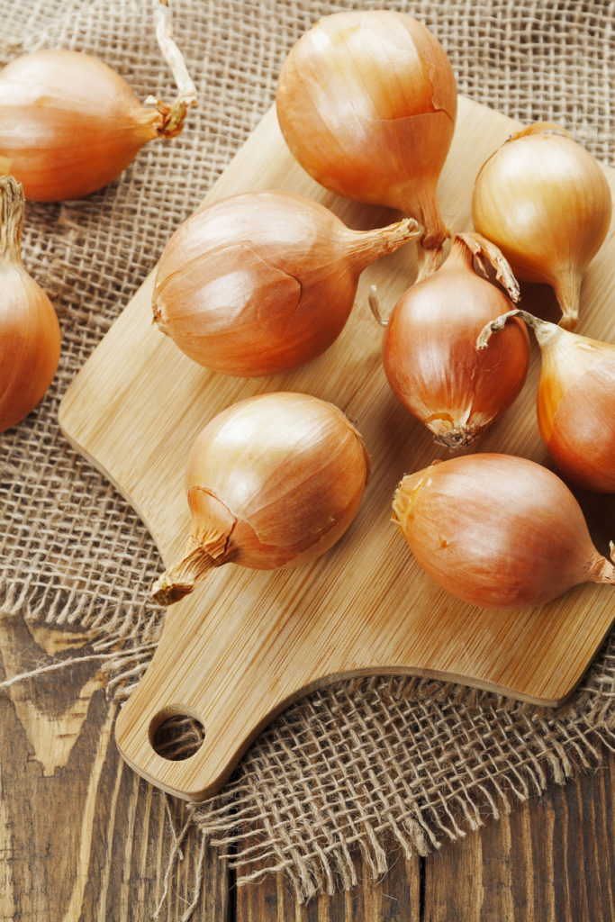 Szép vöröshagymák egy fa deszkán