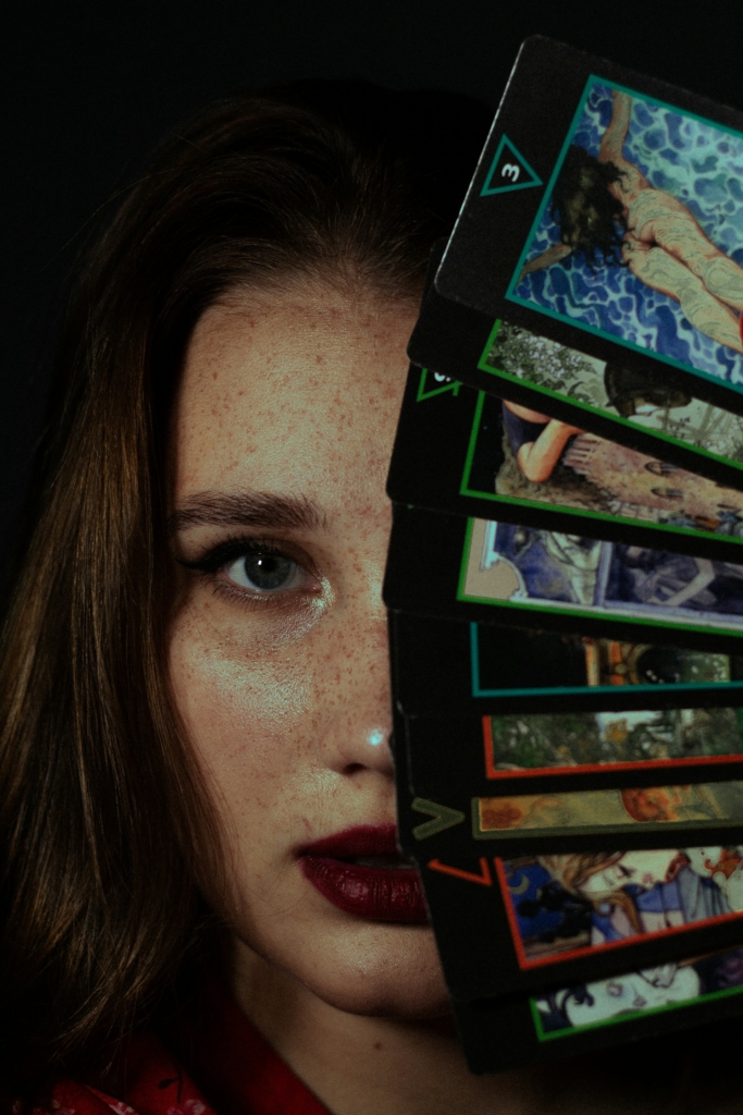 Lány egy csomag Tarot kártyával takarja el a fél arcát