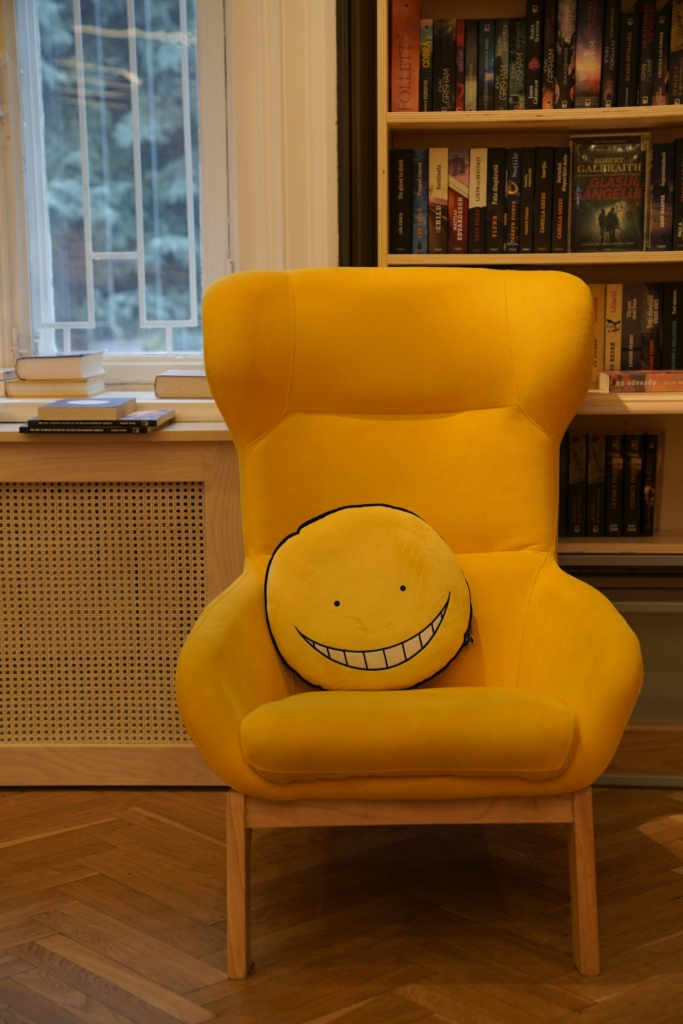 Gúnyosan mosolygós smiley párna egy sárga fotelben