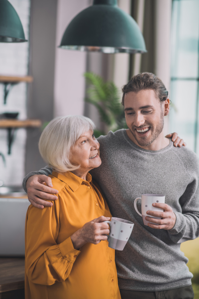 Fiatal felnőtt férfi és idős édesanyja együtt kávéznak