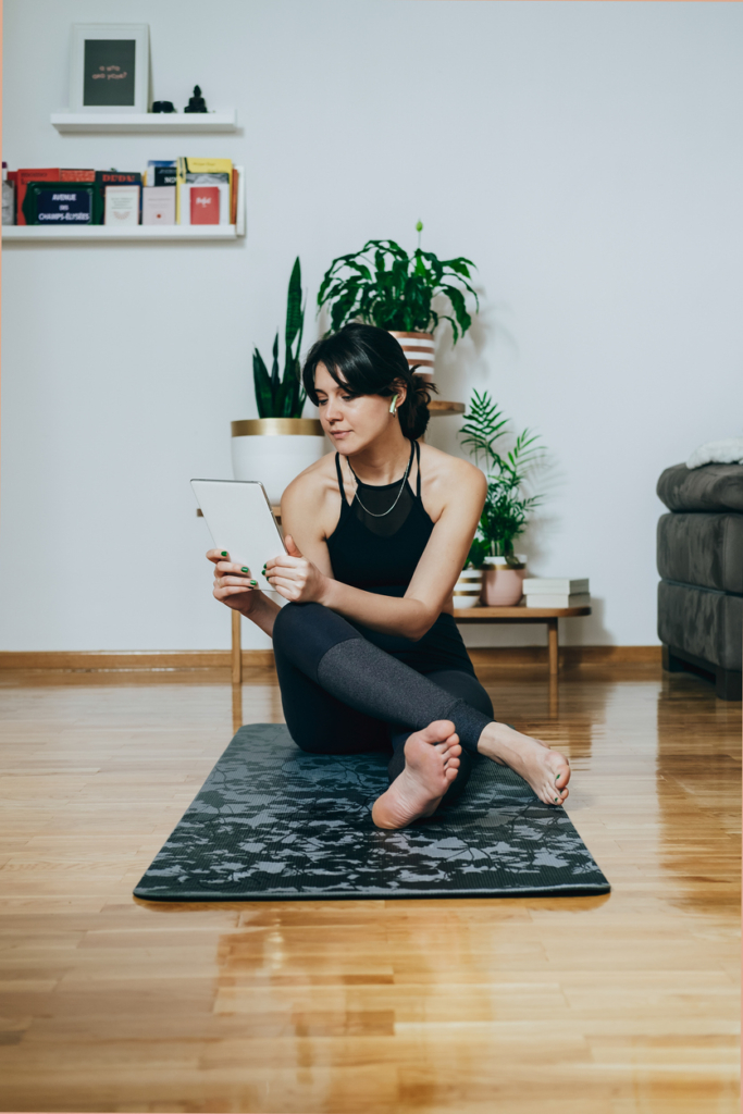 Nő otthon tornázik, közben egy táblagépet néz