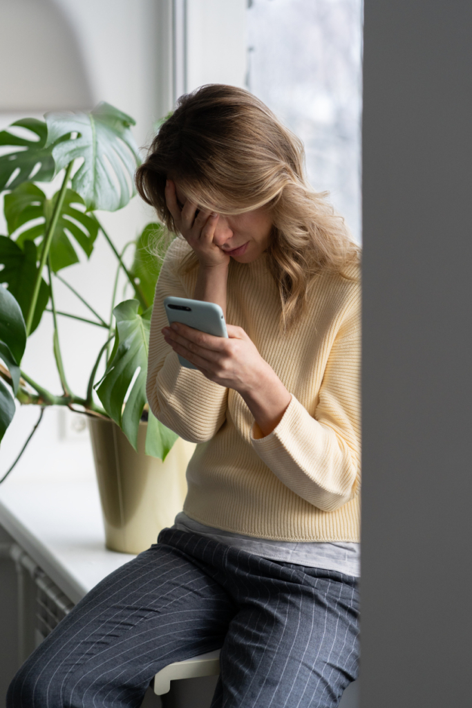 Nő aggódva olvassa a mobiltelefonját