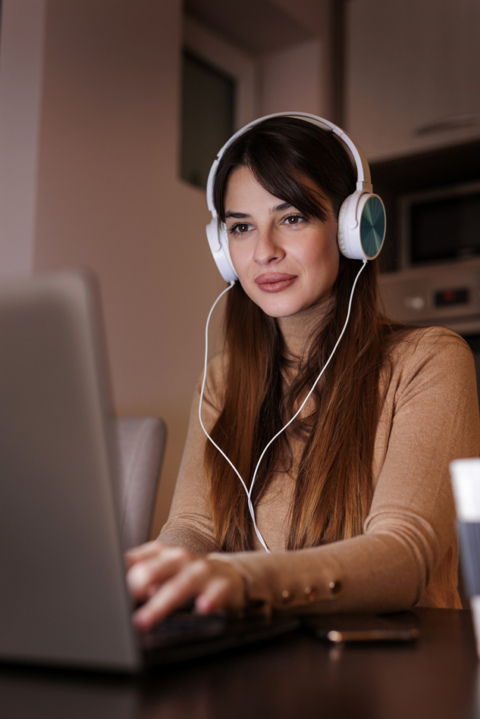 Fiatal nő munka közben zenét hallgat fejhallgatón