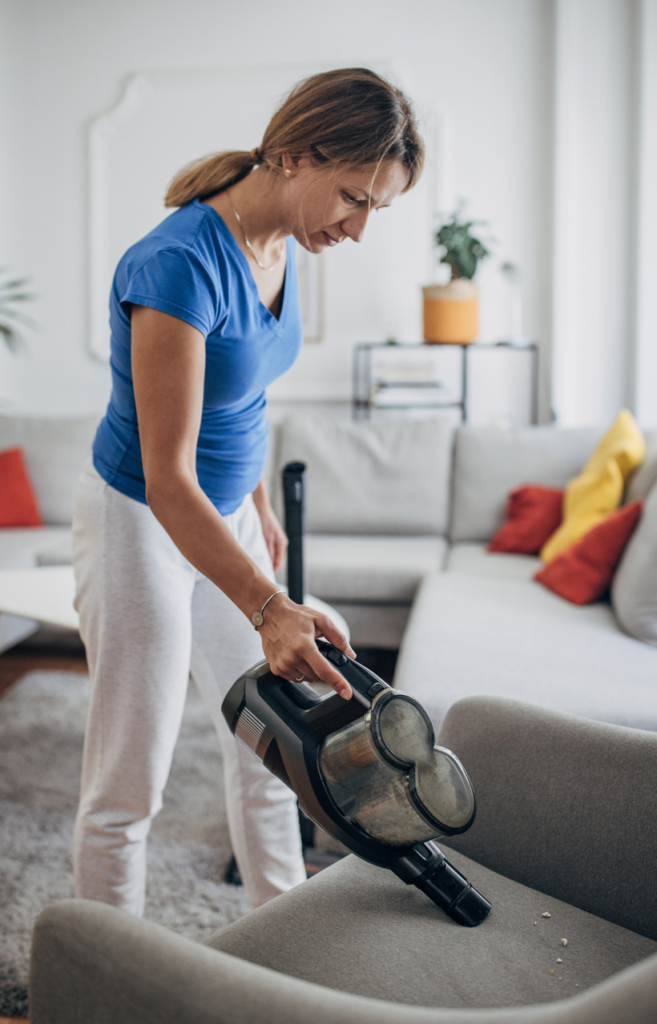 Nő leporszívózza a fotelt