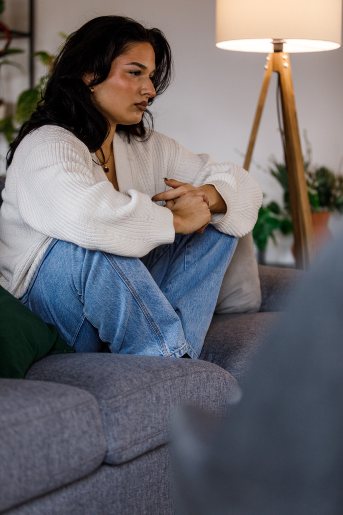 Szomorú, szorongó nő ül a kanapén egyedül