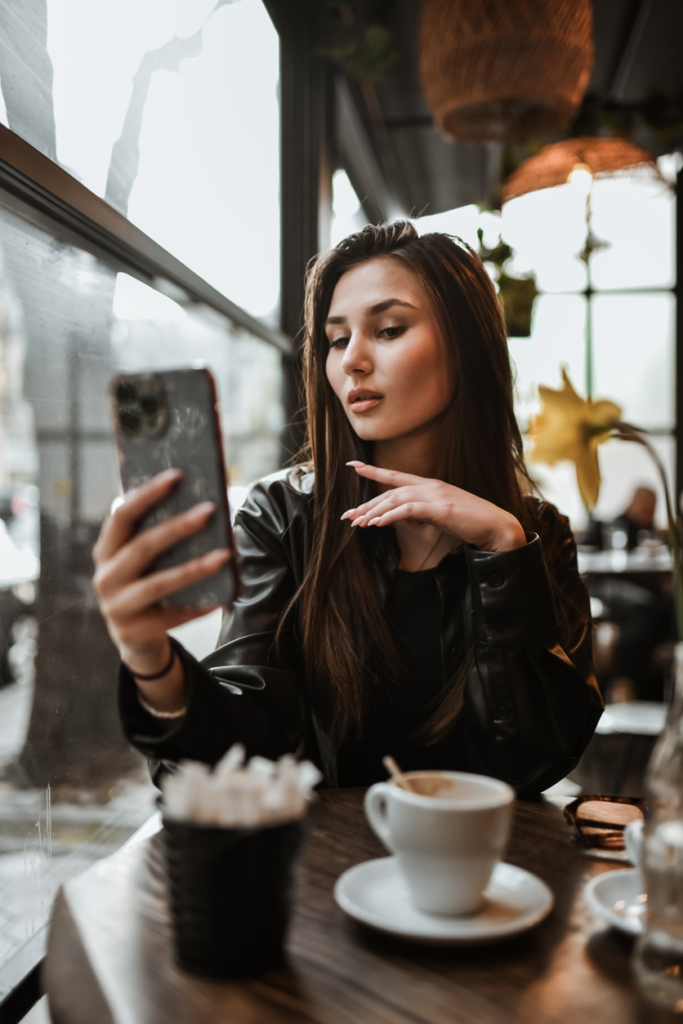 Lány egy kávézóban mobilozik