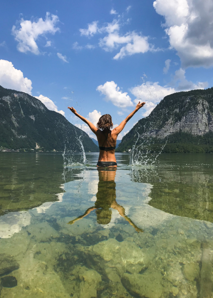 Nő felemelt karral áll a Hallstätter see-ben, Ausztriában