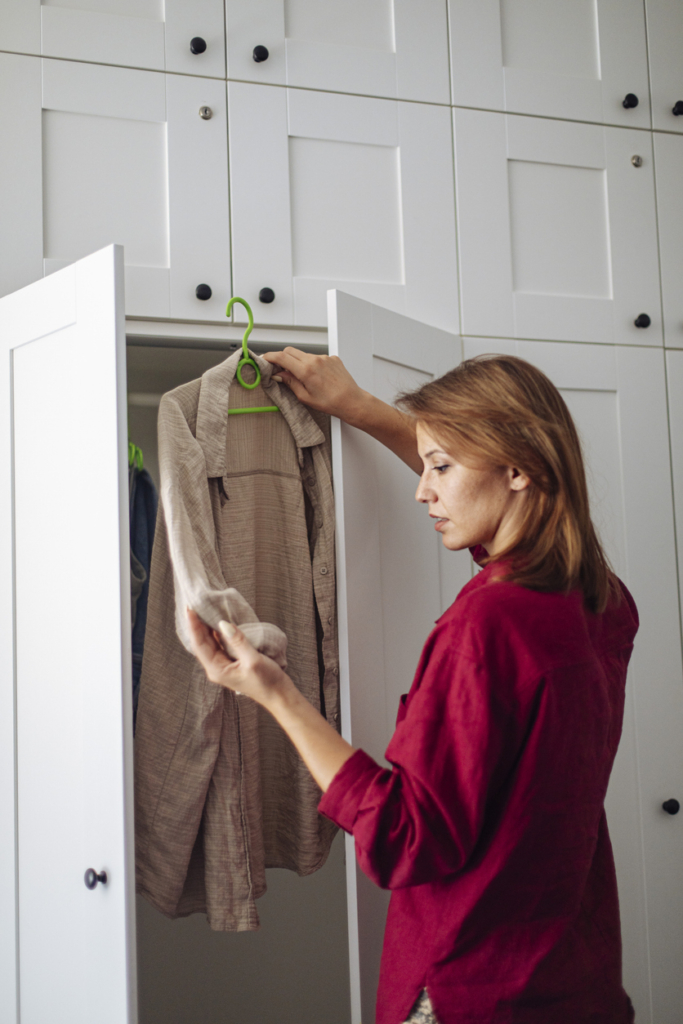 Fiatal nő ruhát vesz ki a szekrényből