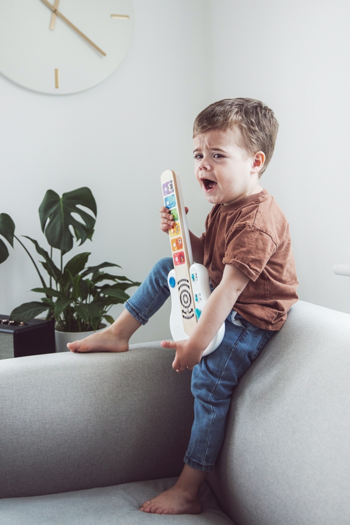 Kisfiú játékgitározás közben ordítva sír