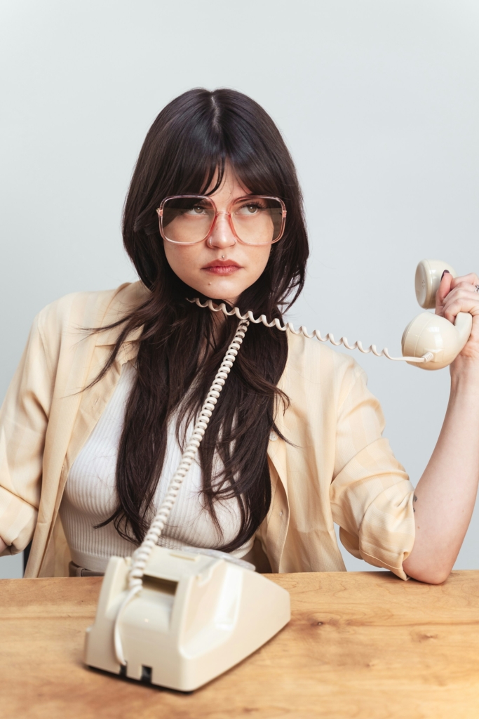 Femme ennuyeuse enroulant un fil de téléphone fixe autour de son cou