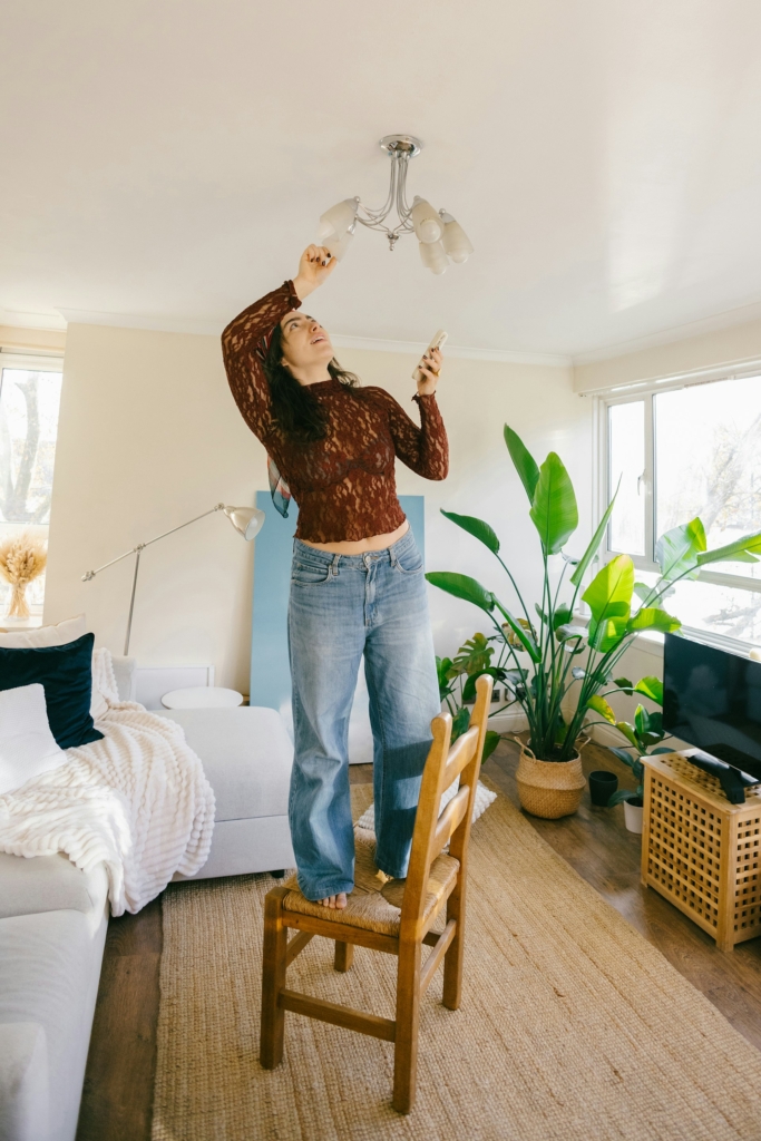 Nő tekeri a csillárban az izzót