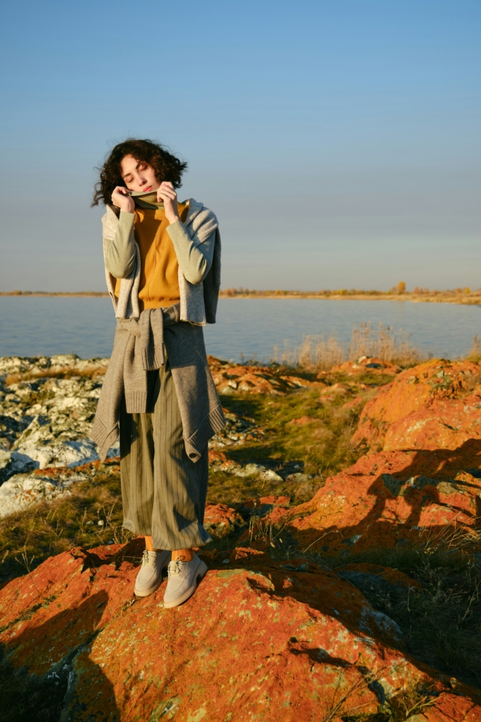 Nő egy tengerparti sziklaszirten áll