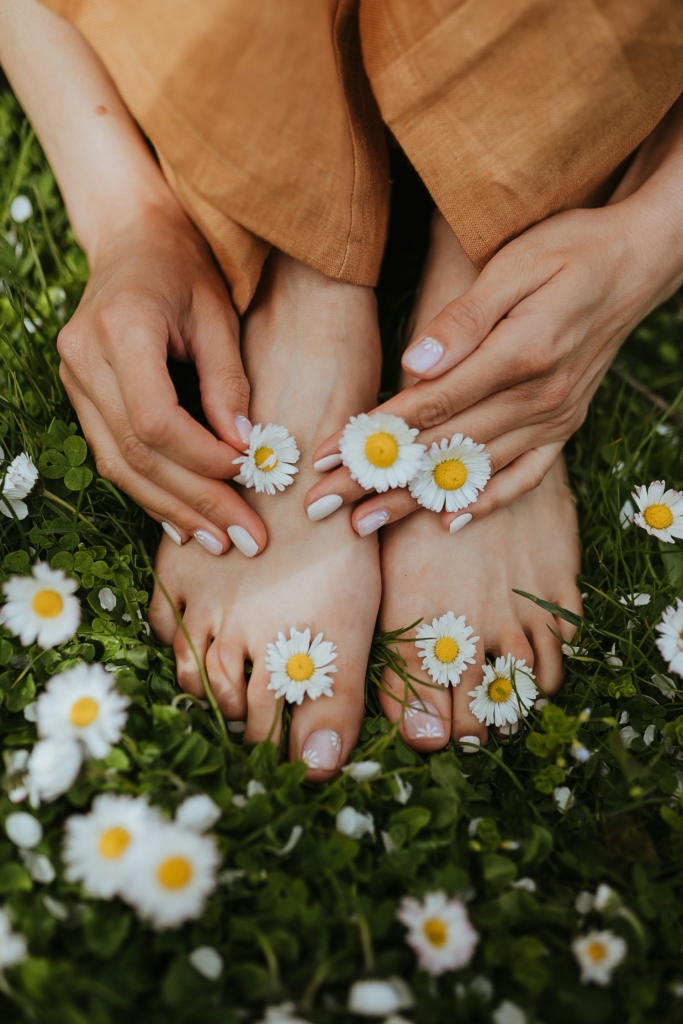 Nő lábujjai között százszorszépek