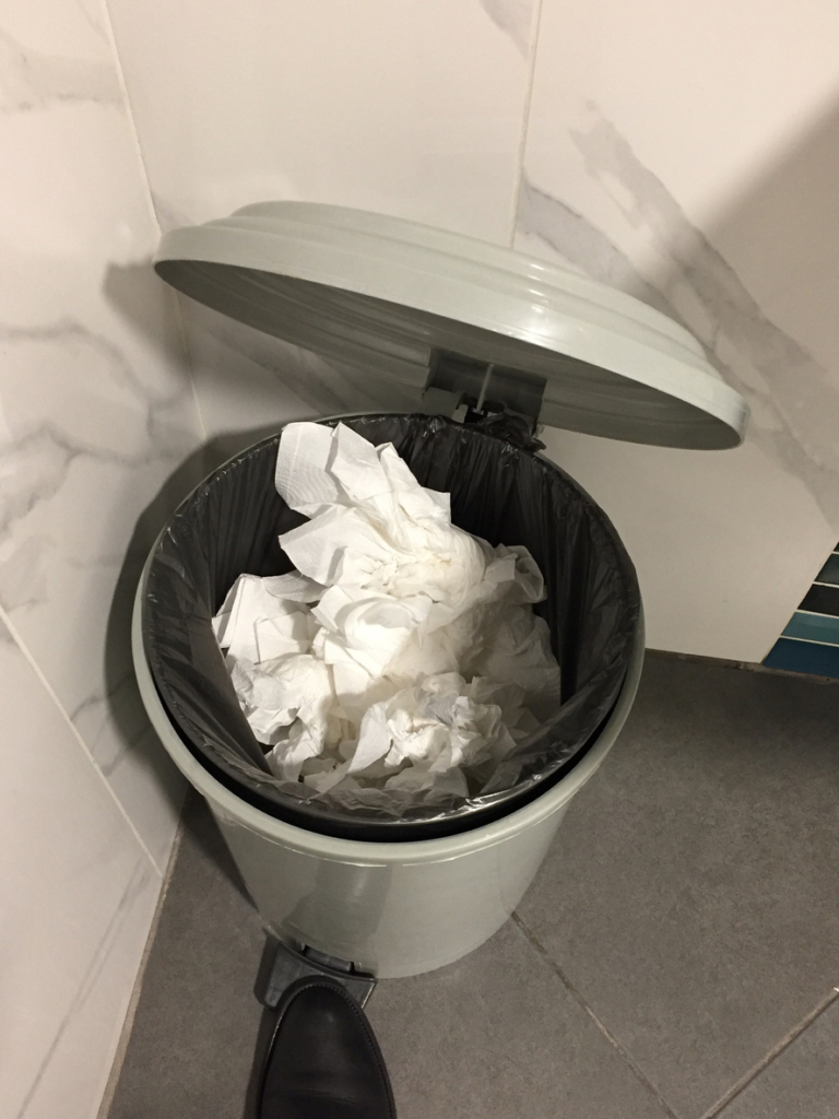 Poubelle de salle de bain remplie de serviettes en papier