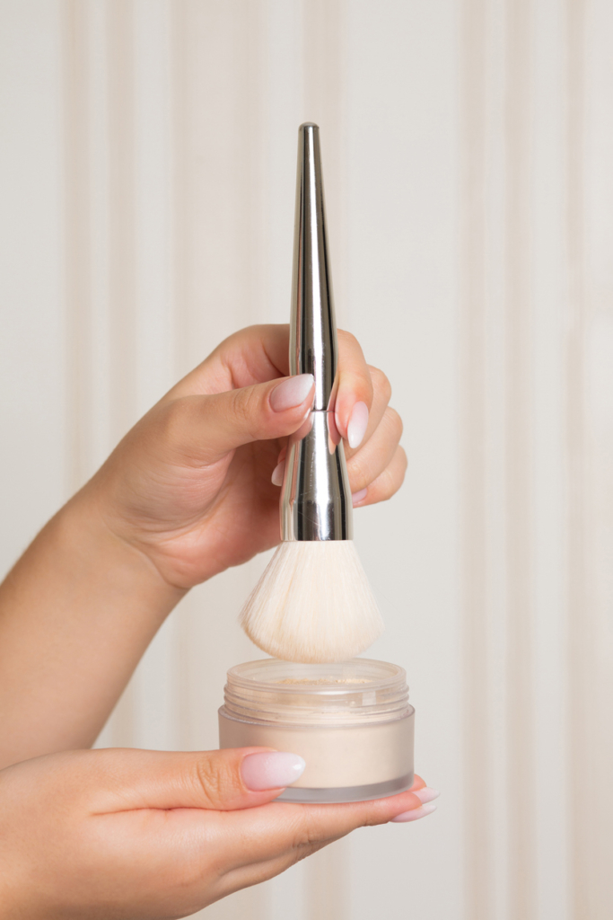 Nő ecsetet márt a porpúderbe, közeli kép