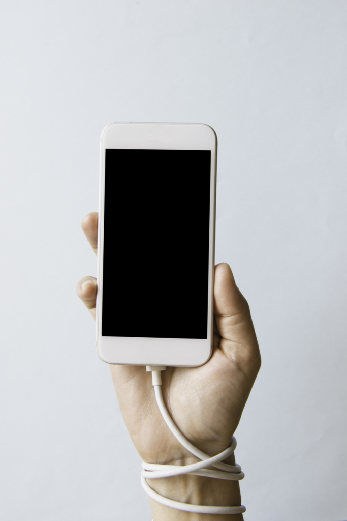 Dépendance au téléphone : câble enroulé autour du poignet d’une femme