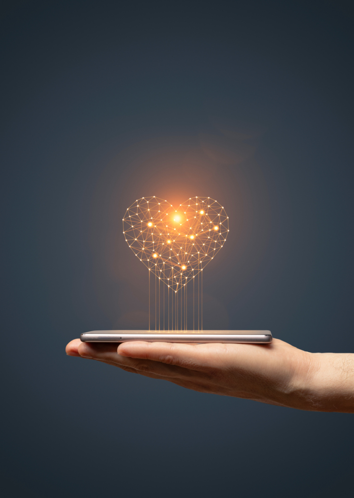 Tenyér okostelefont tart, amiből szív alakú izzó vetül ki