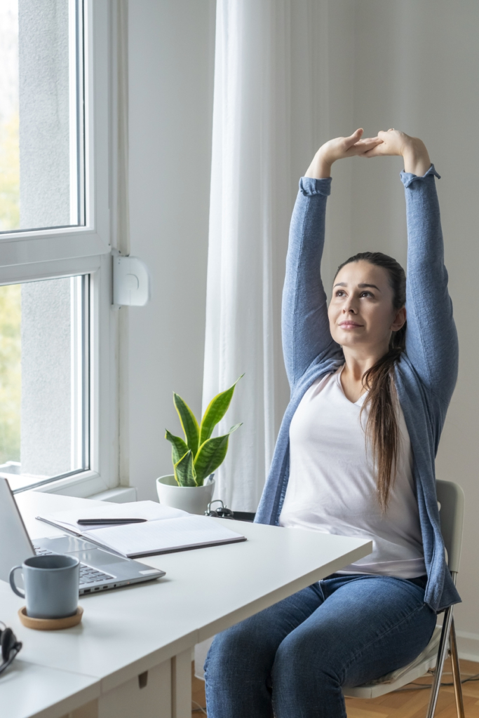 Nő ülőmunka közben magasra nyújtózkodik