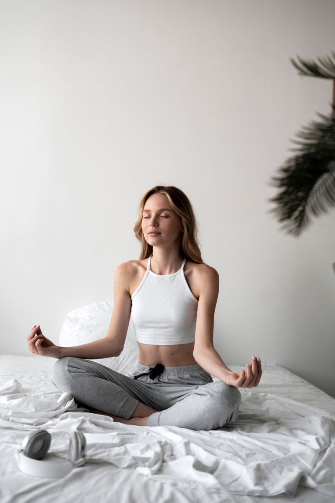 Fiatal nő az ágyon ülve meditál