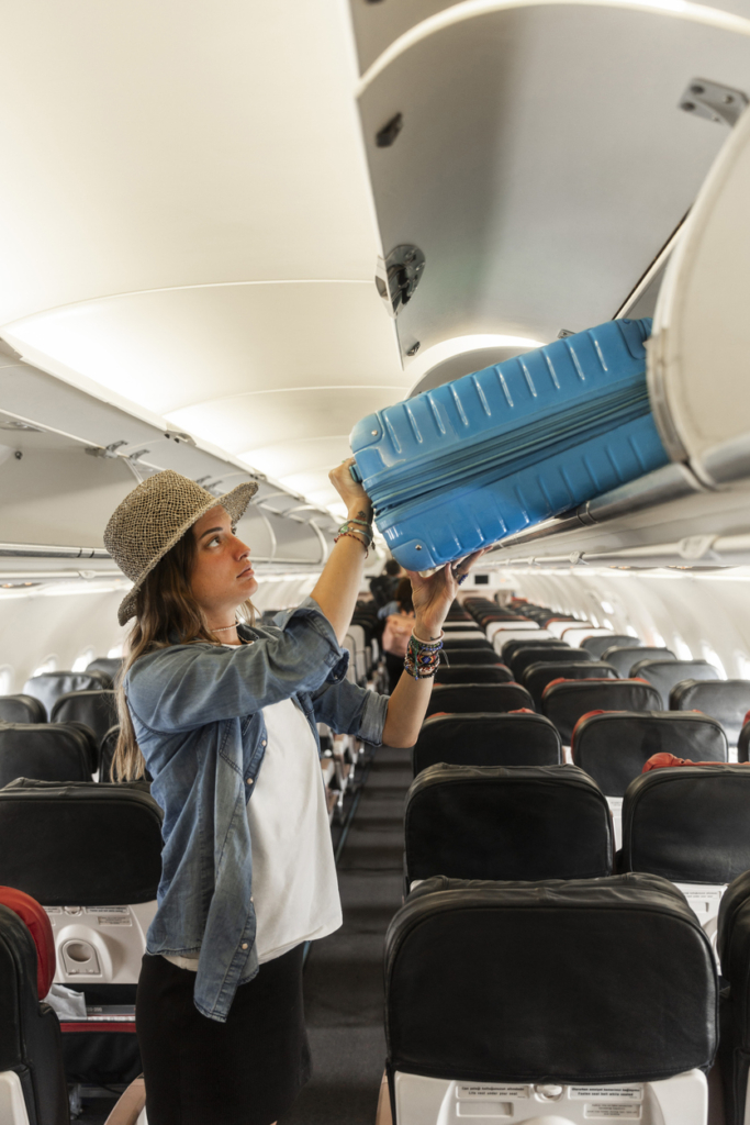 Nő felrakja a bőröndjét a repülőtér csomagtartójába