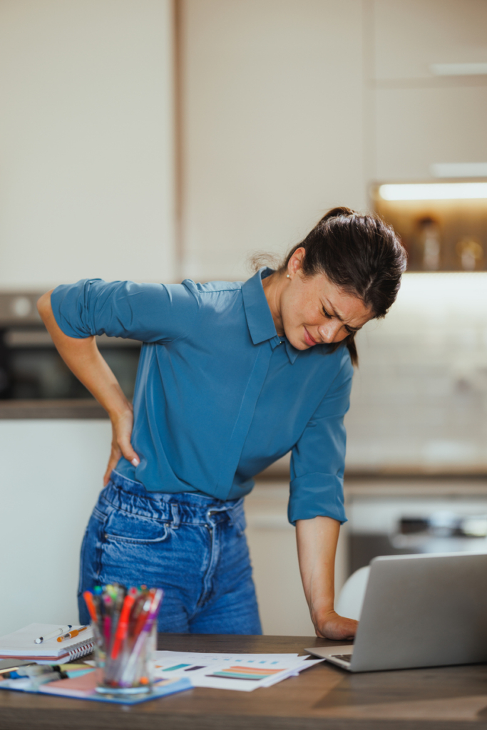 Nő fájlalja a hátát ülőmunka közben, ezért kénytelen felállni