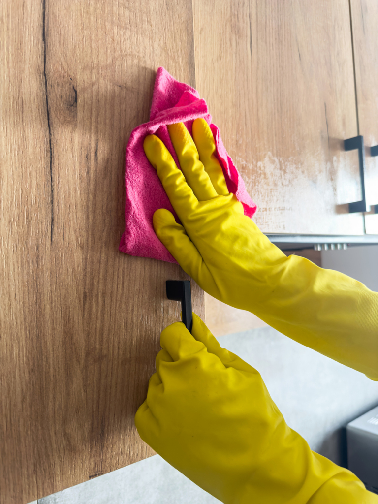 Femme en gants jaunes nettoyant un meuble de cuisine