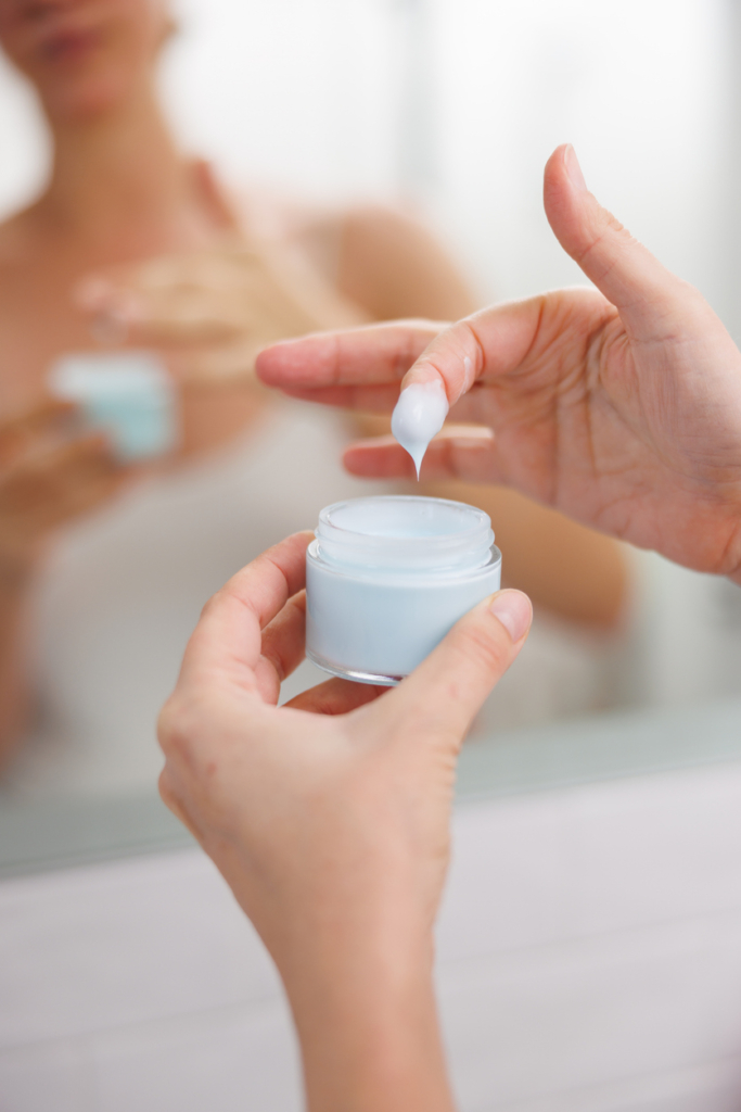 Nő az ujjaival krémet vesz ki egy tégelyből