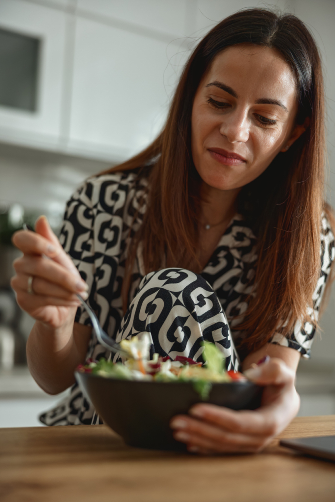Femme souriante déjeunant une salade