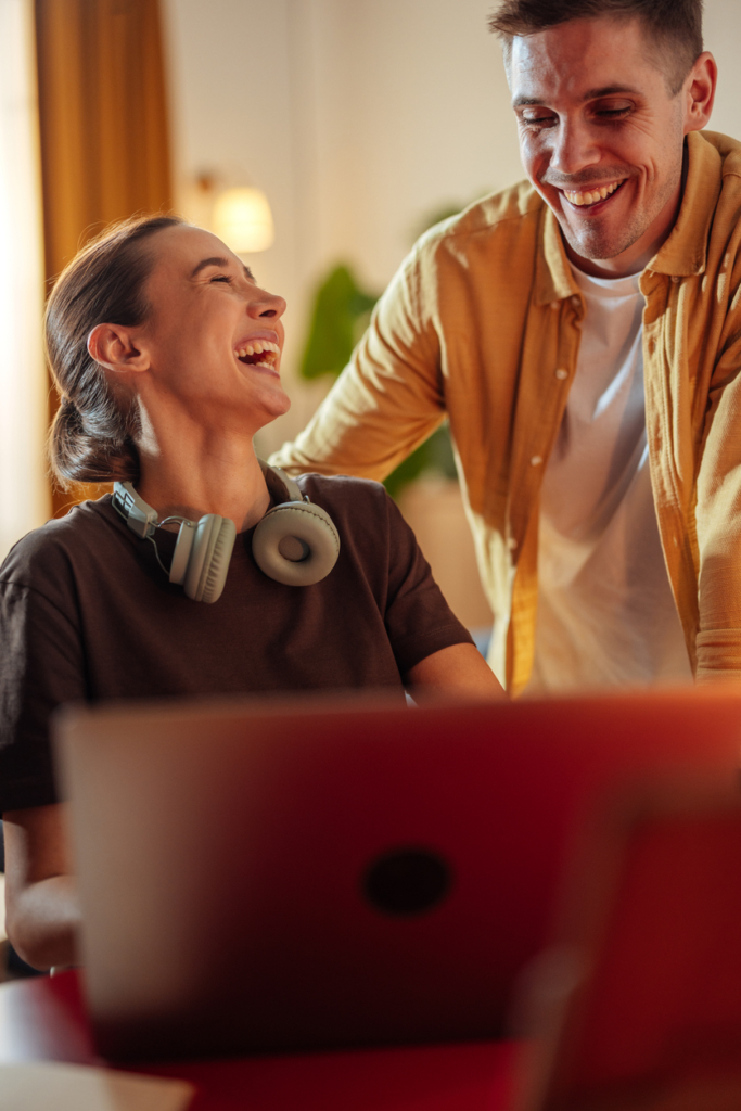 Mann und Frau arbeiten zusammen am Laptop und lachen