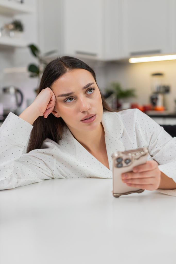 Nő unottan pötyög  atelefonjába