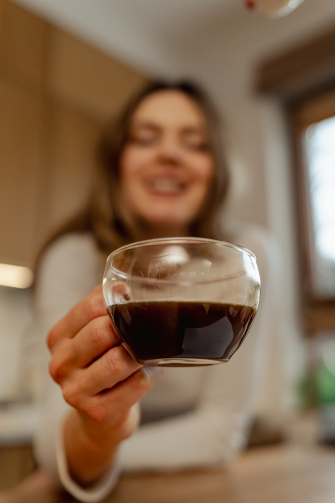 Donna che tiene in mano una tazza di caffè trasparente
