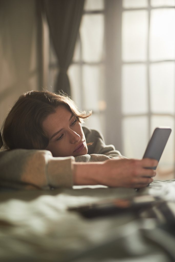 Nő okostelefonnal a kezében, unottan