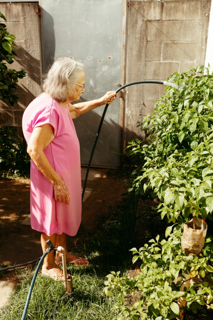 Donna anziana che annaffia le piante in giardino